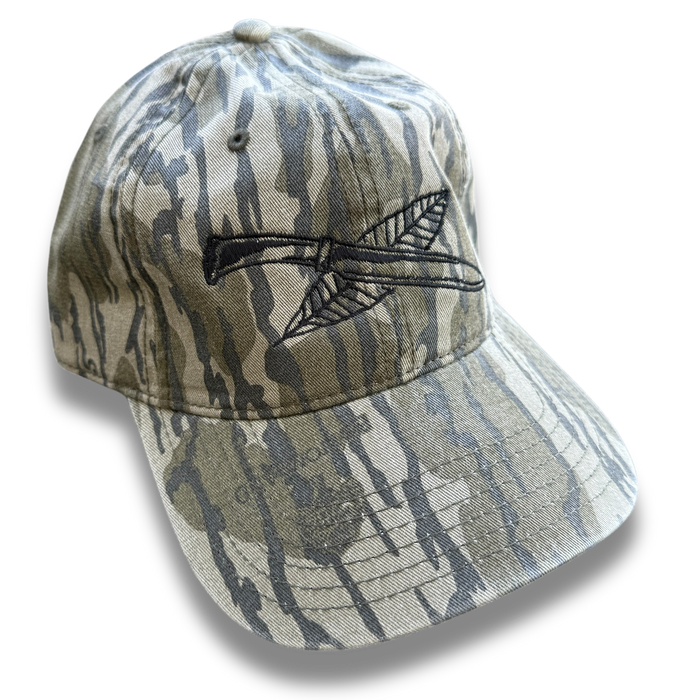 Mossy Oak camouflage trucker hat with black embroidered Nature Reliance School knife and feather logo — durable outdoor cap for bushcraft and survival training.